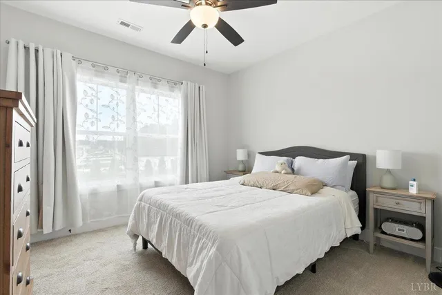 a bedroom with a large bed and a chandelier fan