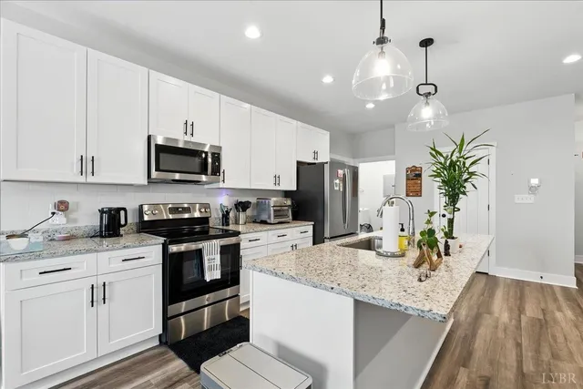 a kitchen with granite countertop a sink stainless steel appliances and white cabinets