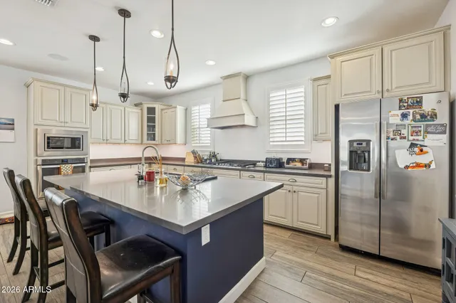 a kitchen with stainless steel appliances granite countertop a refrigerator a sink dishwasher a stove and white cabinets with wooden floor