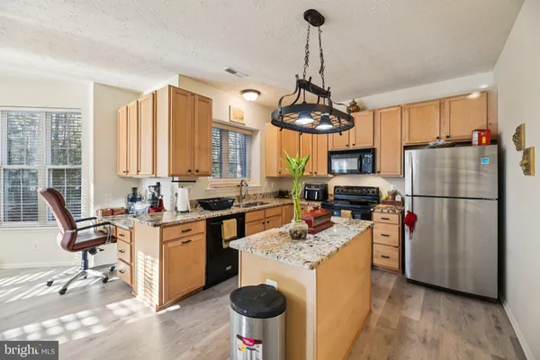 a kitchen with a refrigerator a stove a sink dishwasher a dining table and chairs with wooden floor