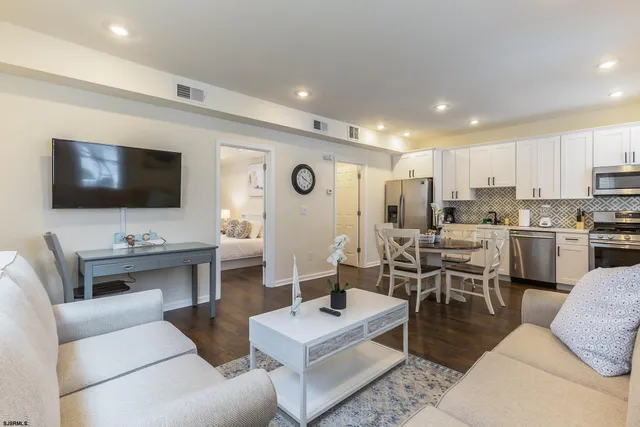 a living room with furniture kitchen view and a flat screen tv