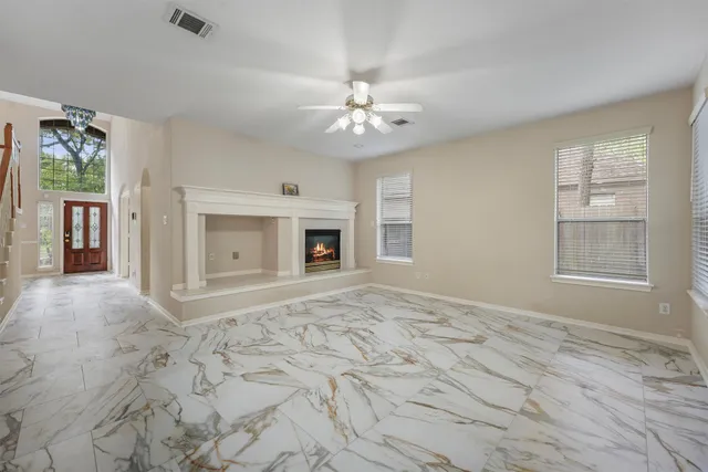 an empty room with chandelier fan and windows