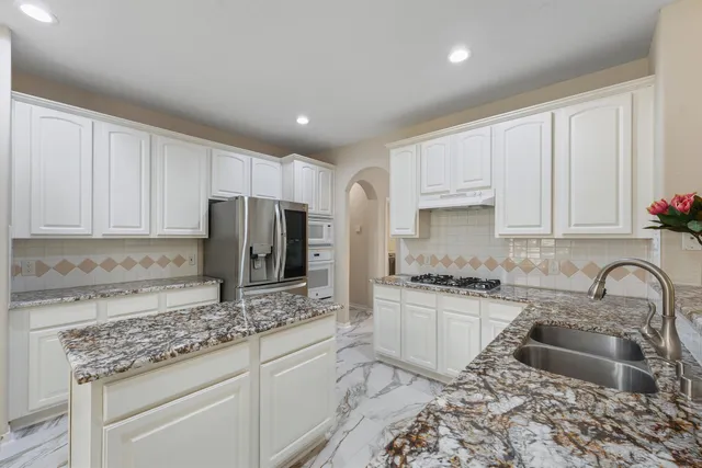 a kitchen with granite countertop a sink stove and refrigerator