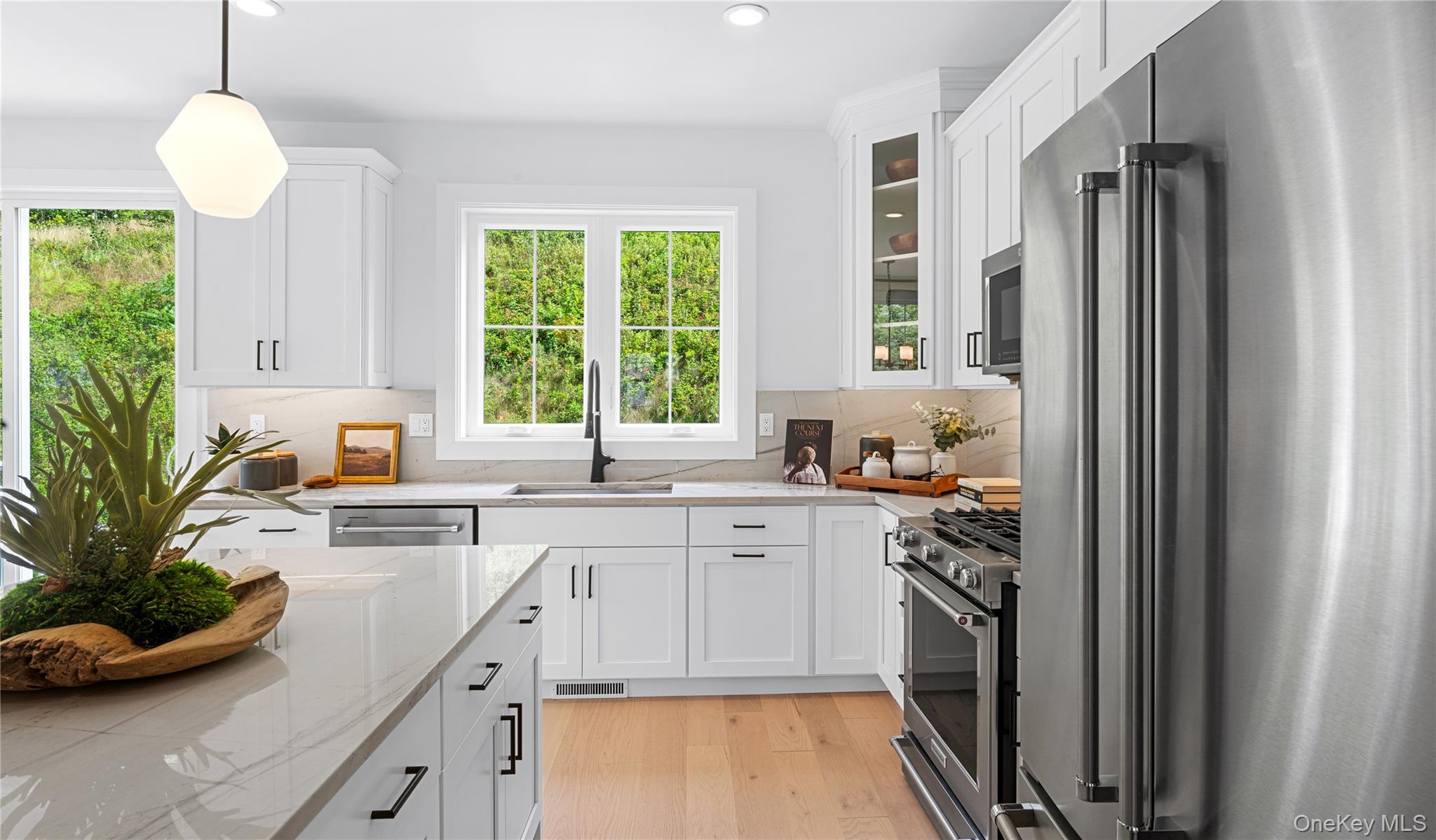 5102 Teaberry Lane, Unit 35 Fishkill, NY 12524 - Photo 4 of 9 Kitchen with appliances with stainless steel finishes, pendant lighting, white cabinets, glass insert cabinets, and light wood-type flooring