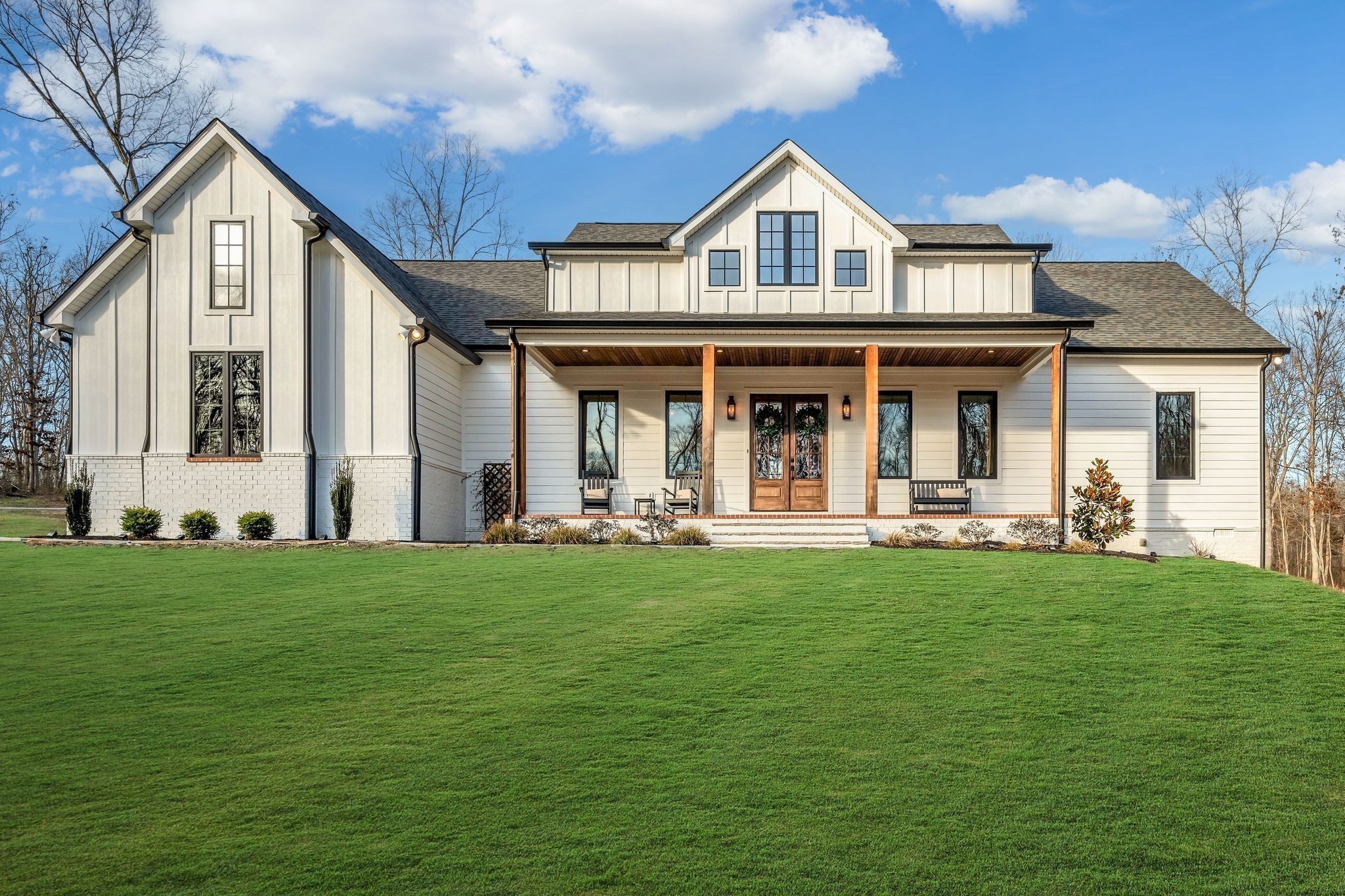 a view of a white house with a big yard and potted plants