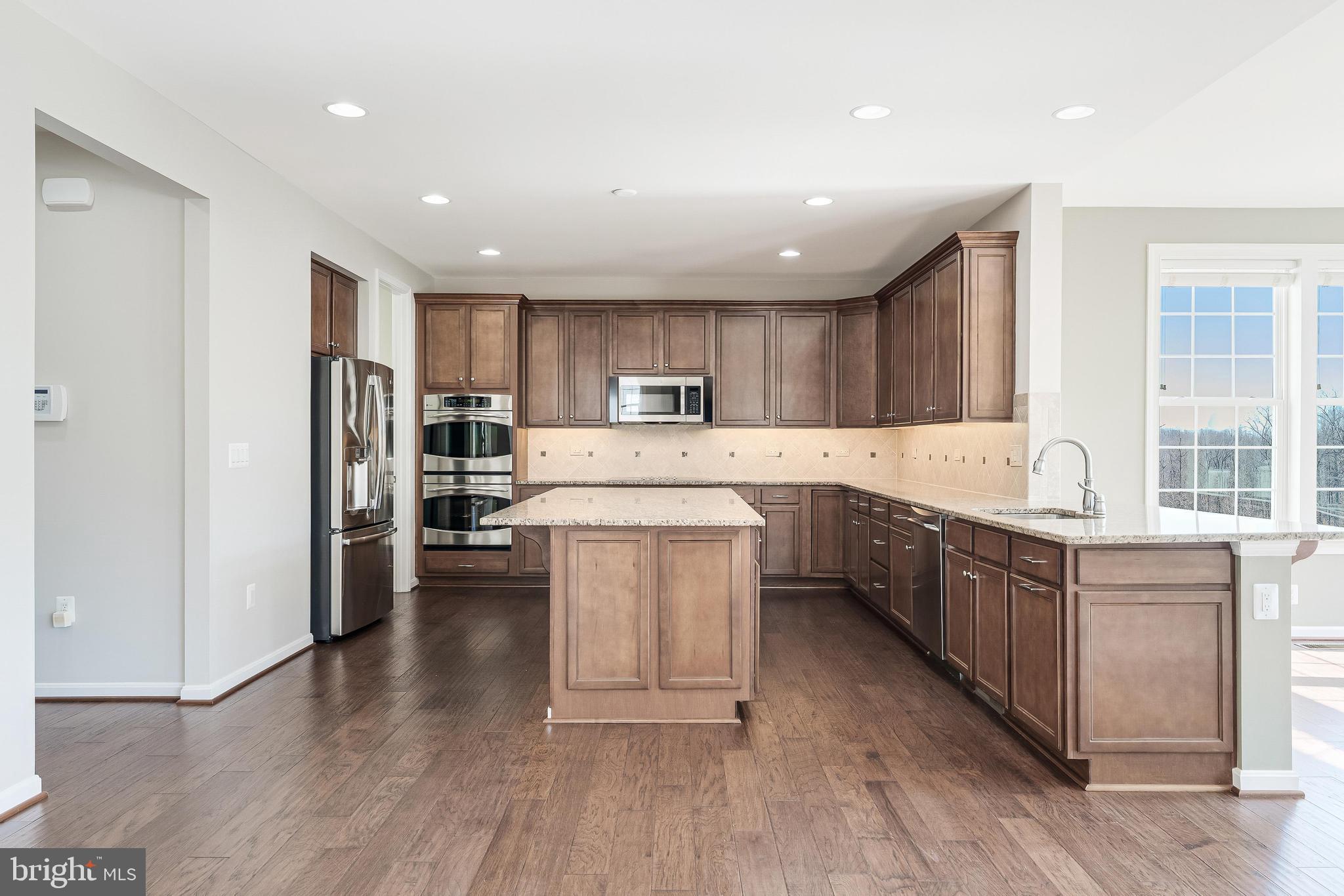 18747 Pier Trail Drive Triangle, VA 22172 - Photo 39 of 84 a kitchen with kitchen island granite countertop wooden floors and stainless steel appliances