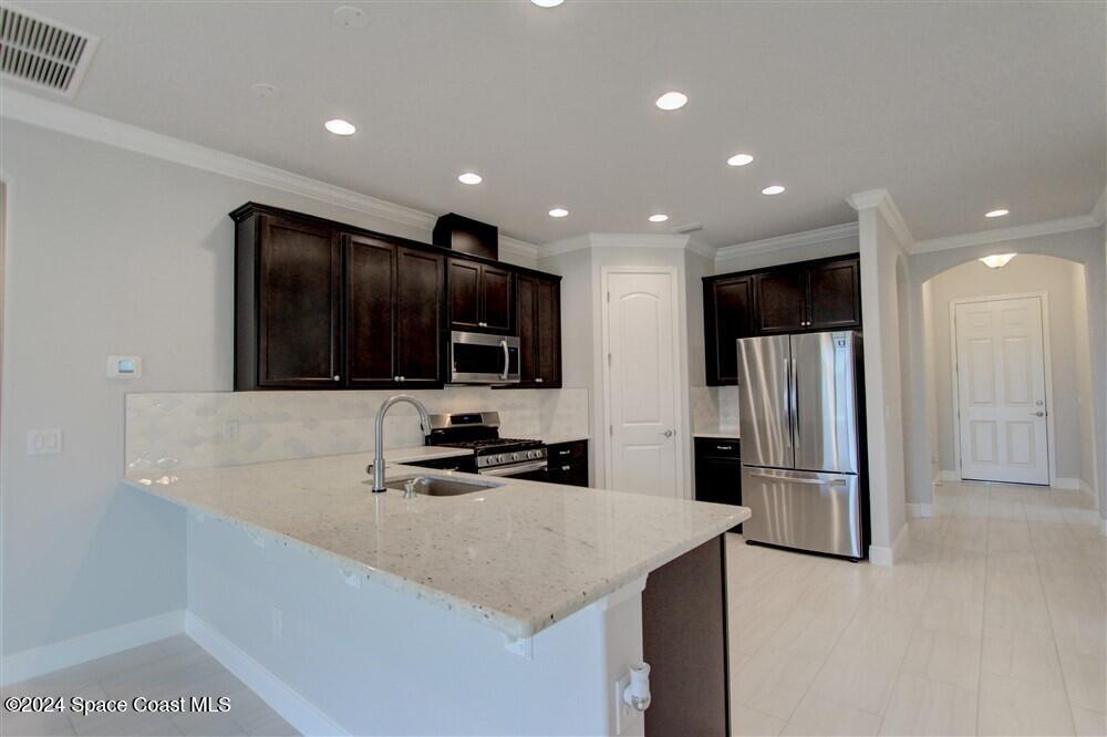 3267 Addison Drive Melbourne, FL 32940 - Photo 10 of 37 a kitchen with stainless steel appliances a refrigerator microwave stove sink and cabinets