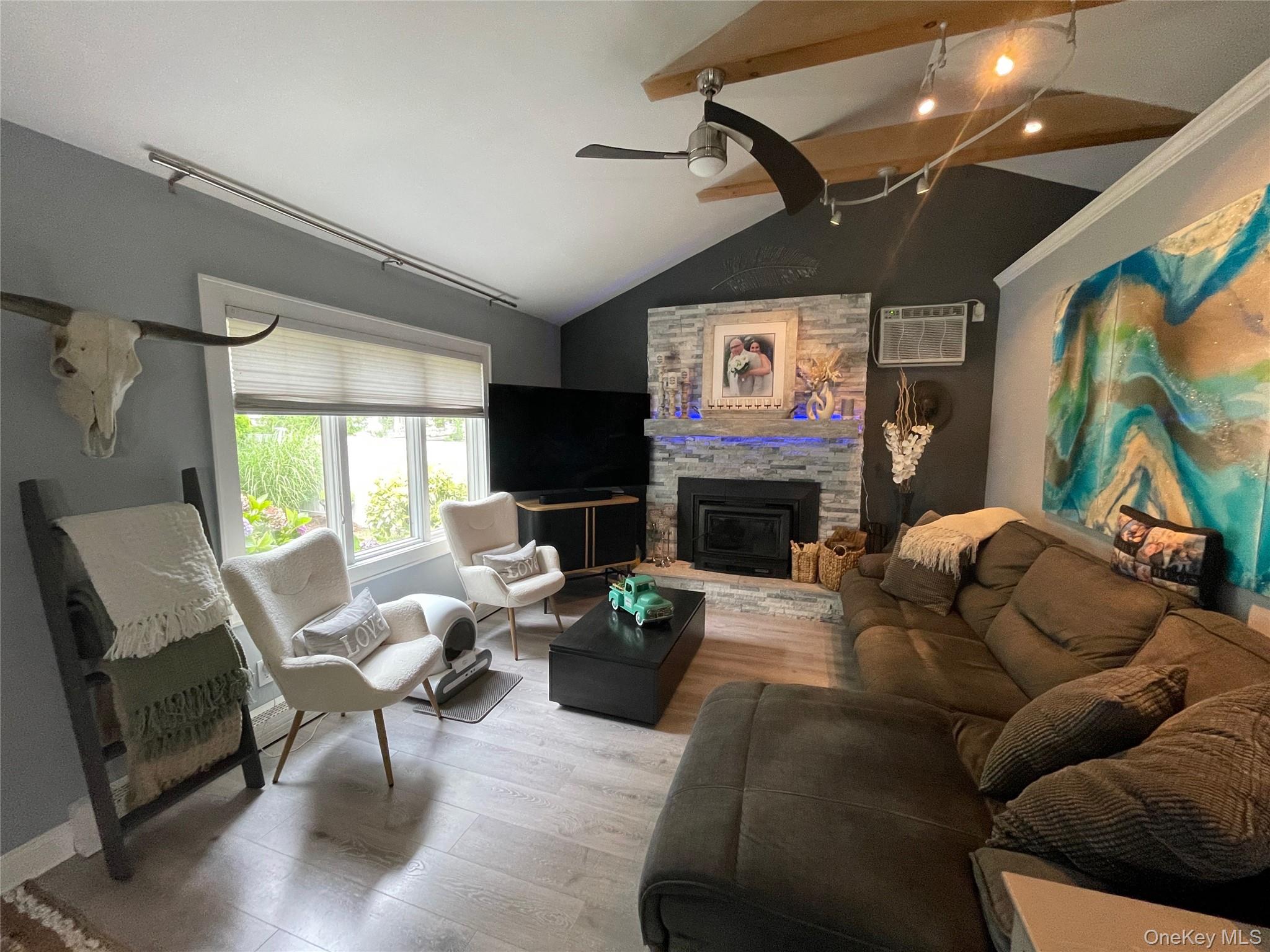 30 Classon Avenue Mastic, NY 11950 - Photo 11 of 21 Living room with vaulted ceiling, wood finished floors, ceiling fan, a fireplace, and an AC wall unit