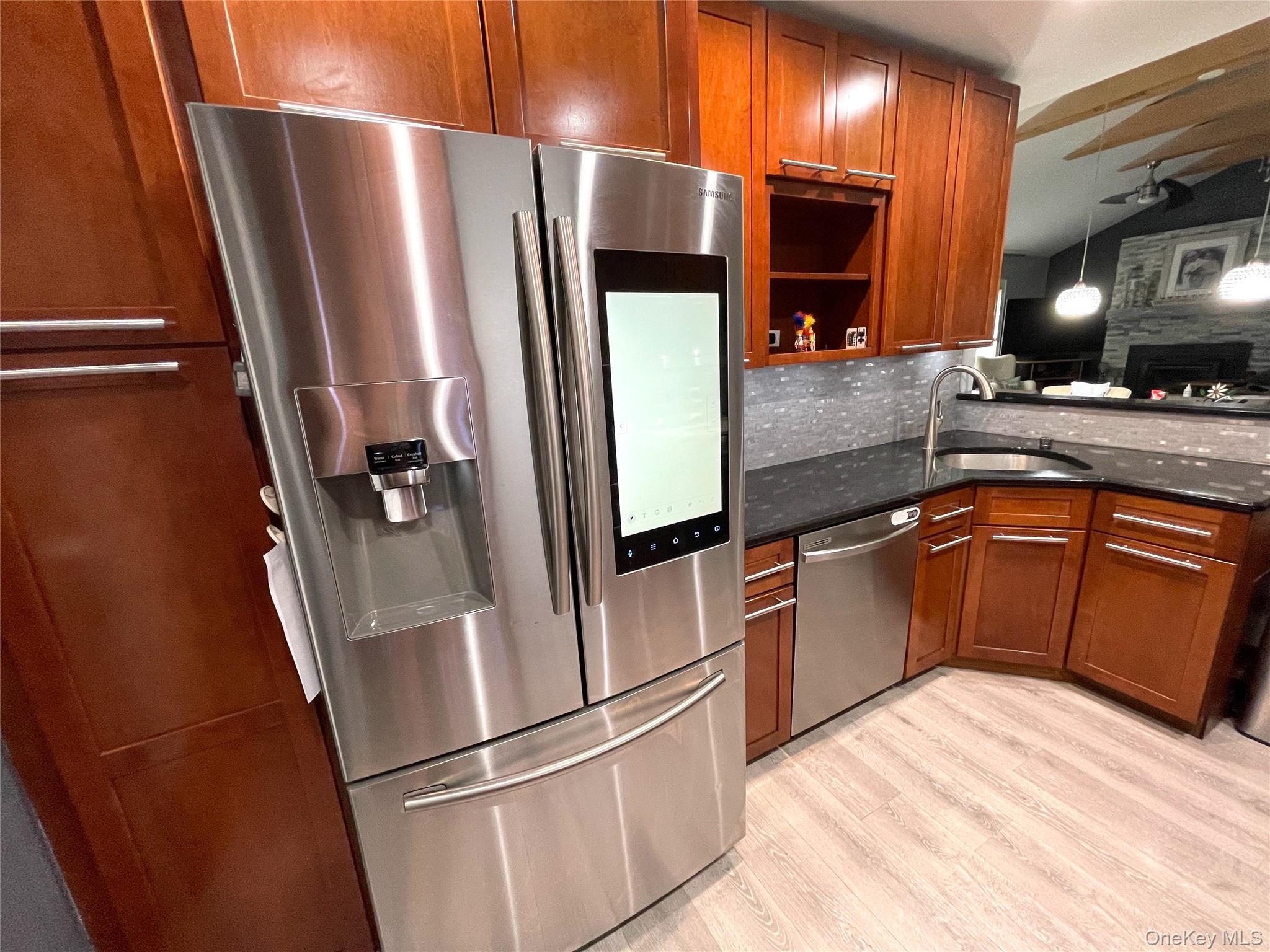 30 Classon Avenue Mastic, NY 11950 - Photo 4 of 21 Kitchen with appliances with stainless steel finishes, dark stone countertops, lofted ceiling, light wood-style floors, and brown cabinets
