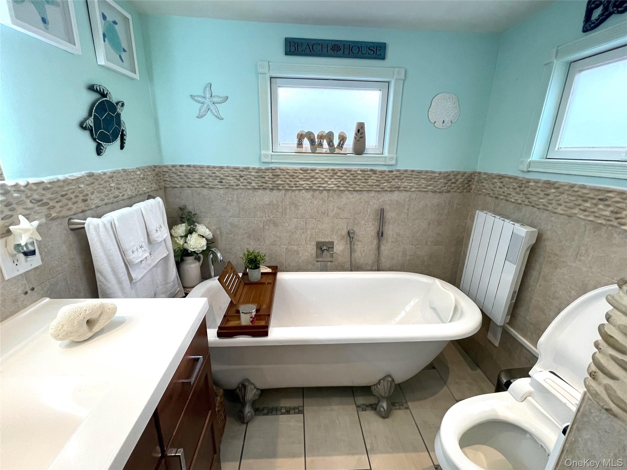 30 Classon Avenue Mastic, NY 11950 - Photo 10 of 21 Bathroom featuring vanity, a soaking tub, a wainscoted wall, light tile patterned flooring, and tile walls