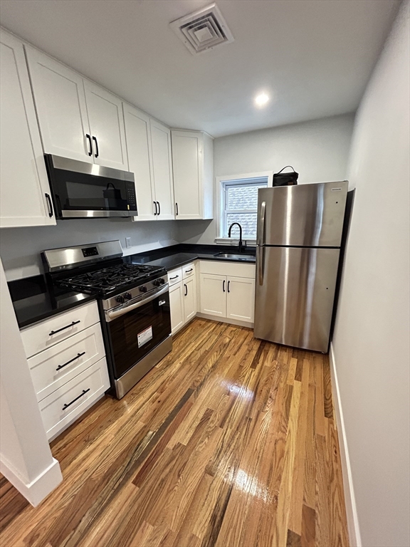 a kitchen with white cabinets and stainless steel appliances