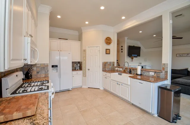 a large kitchen with stainless steel appliances a sink a stove a refrigerator and cabinets
