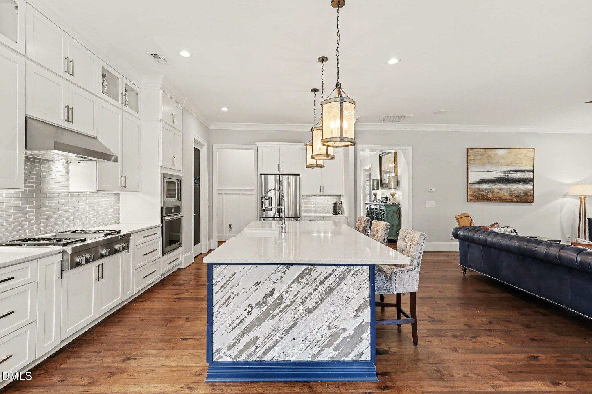 7433 Sextons Creek Drive Raleigh, NC 27614 - Photo 3 of 20 a large kitchen with kitchen island a stove a sink a center island and a wooden floor