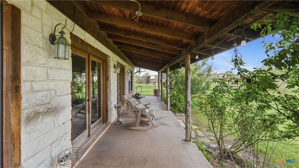 127 Offer Llano, TX 78643 - Photo 26 of 40 Expansive covered porch featuring a natural wood ceiling, wood support beams, string lighting, and direct access to the interior via double glass doors