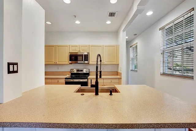 a living room with stainless steel appliances kitchen island granite countertop a stove a sink a refrigerator with white cabinets and wooden floor