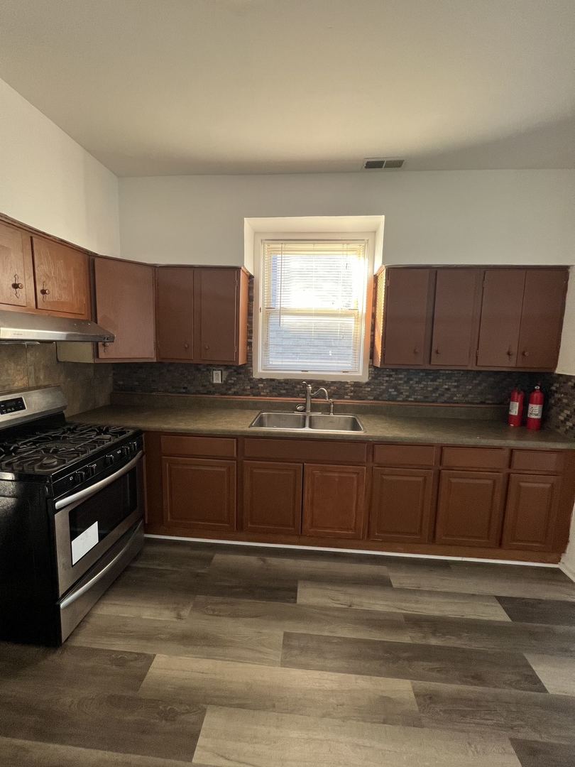 4533 South Richmond Street, Unit 2 Chicago, IL 60632 - Photo 3 of 7 a kitchen with granite countertop a stove a sink and a microwave