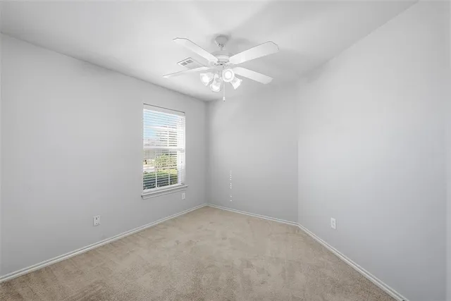 an empty room with a window and a fan