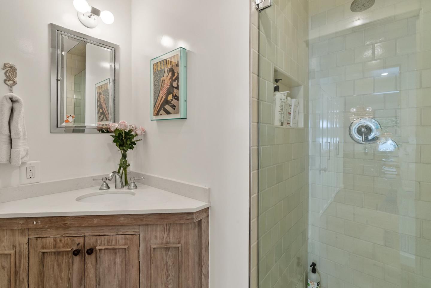 25990 Junipero Street Carmel, CA 93923 - Photo 18 of 26 a bathroom with a sink a mirror a glass door a shower and a mirror
