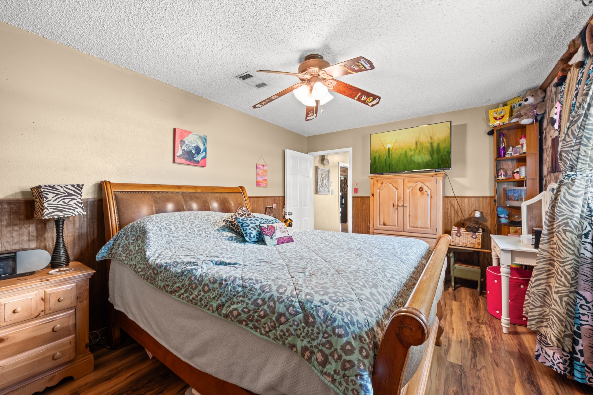 15602 Fir Road Santa Fe, TX 77517 - Photo 25 of 42 Generously sized secondary bedroom with wood-look flooring, ceiling fan, and ample space for larger furnishings. Large windows and warm finishes create a bright and comfortable retreat with flexible use options.