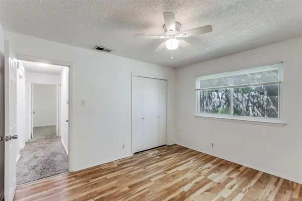 a view of an empty room with wooden floor and chandelier fan