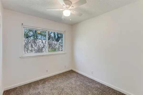 an empty room with a window and a fan