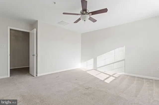 an empty room with a ceiling fan and carpet