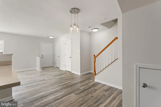 a view of an empty room with wooden floor and stairs