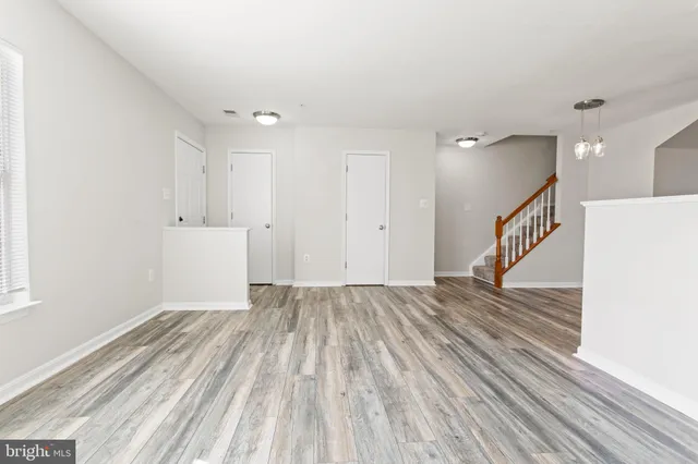 a view of an empty room with wooden floor and stairs
