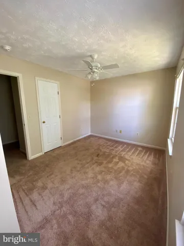 an empty room with a ceiling fan and window