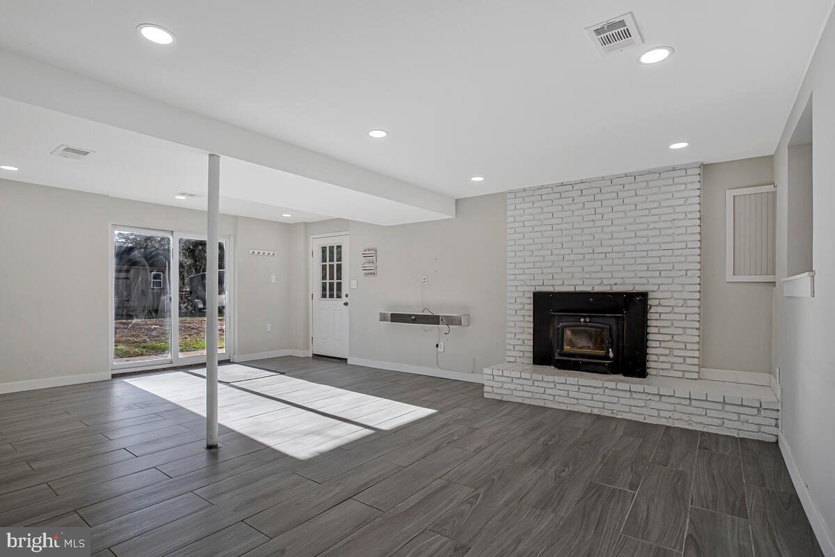 735 Whitehall Beach Road Annapolis, MD 21409 - Photo 18 of 35 an empty room with wooden floor and fireplace