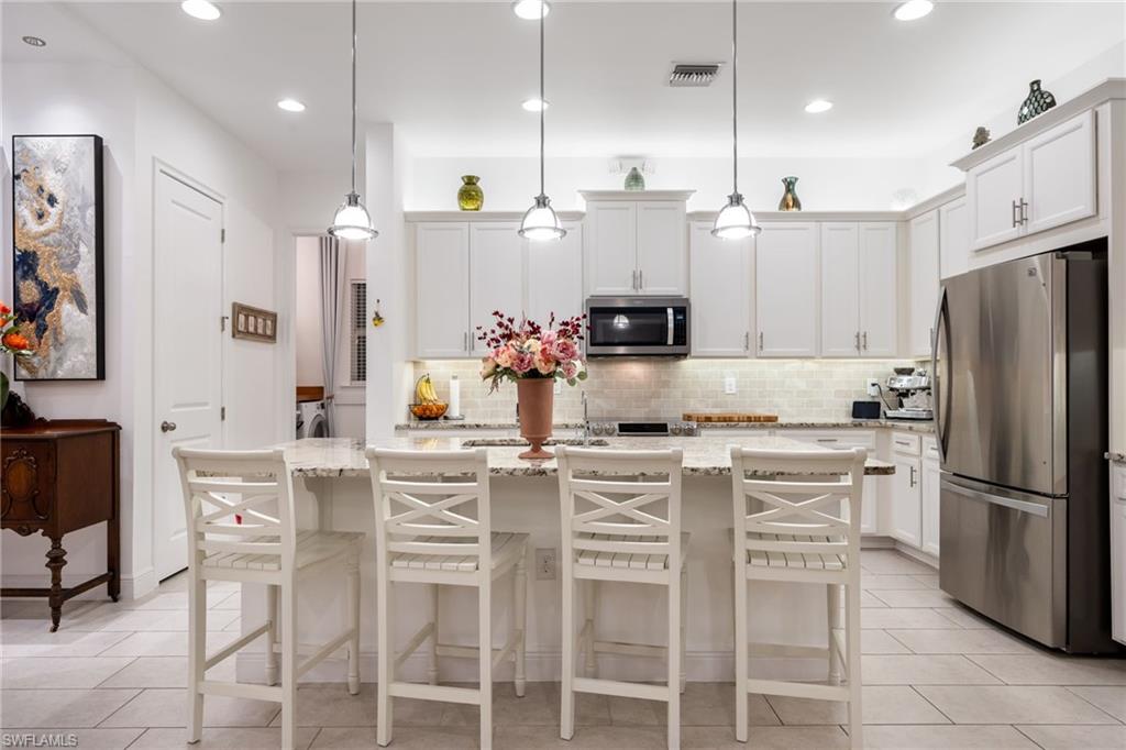 3620 Pilot Circle Naples, FL 34120 - Photo 17 of 49 a kitchen with stainless steel appliances kitchen island granite countertop a table chairs microwave and cabinets