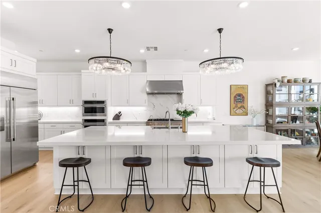 a kitchen with stainless steel appliances kitchen island granite countertop a table chairs stove and white cabinets