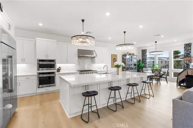 a kitchen with kitchen island granite countertop a stove a oven a dining table and chairs with wooden floor