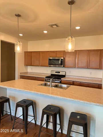 a kitchen with stainless steel appliances granite countertop a sink a stove and chairs