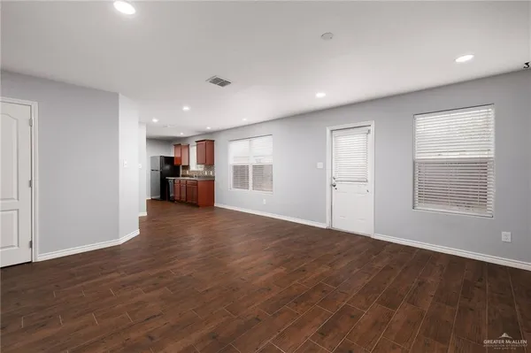 a view of empty room with wooden floor and window