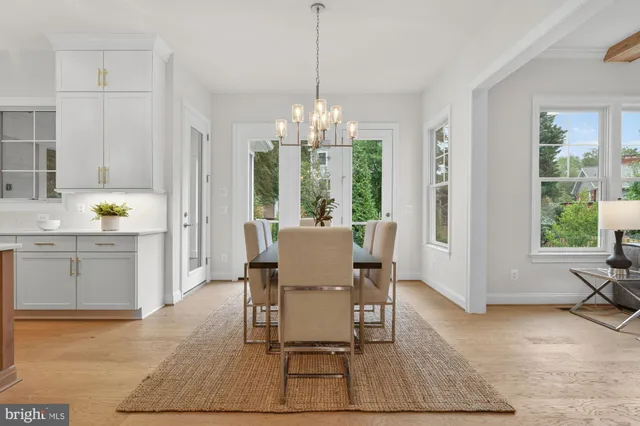 a kitchen with stainless steel appliances granite countertop a stove top oven a sink a dining table and chairs with wooden floor