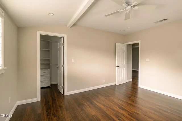 an empty room with wooden floor closet and windows