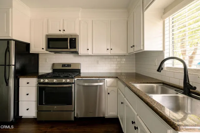 a kitchen with granite countertop a sink stainless steel appliances and cabinets