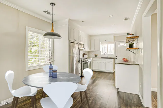 a kitchen that has a dining table chairs stainless steel appliances and cabinets