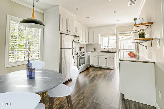 a kitchen with kitchen island a stove a table and chairs in it
