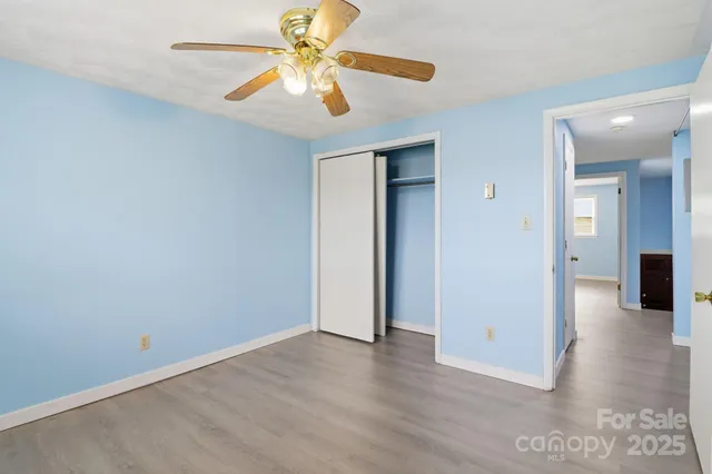 an empty room with closet and a chandelier fan