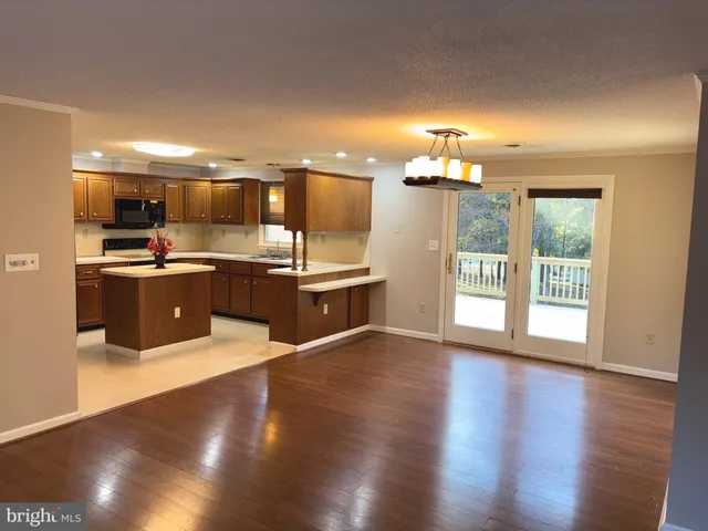 a view of kitchen with kitchen island a sink a stove and a refrigerator with wooden floor