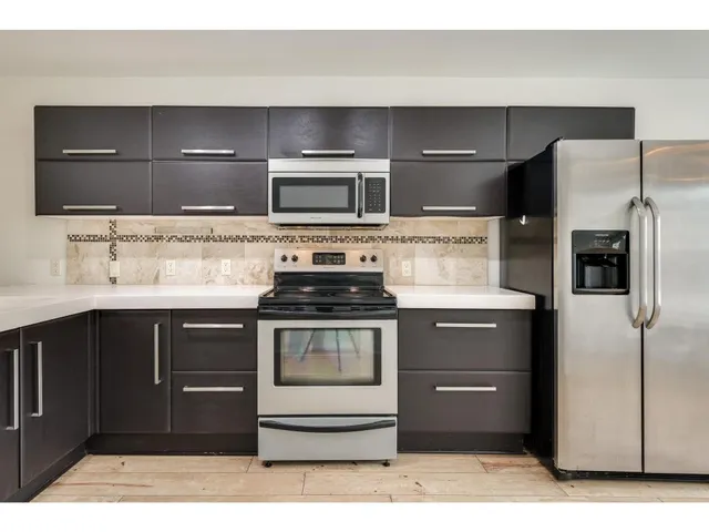 a kitchen with stainless steel appliances kitchen island granite countertop a stove and a microwave