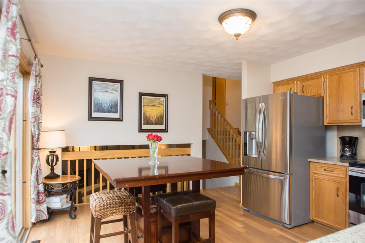 7068 Rye Ridge Trail Cherry Valley, IL 61016 - Photo 10 of 23 a kitchen with stainless steel appliances granite countertop a refrigerator a stove a sink a dining table and chairs with wooden floor
