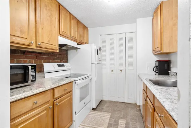 a kitchen with stainless steel appliances granite countertop a sink a stove and a refrigerator
