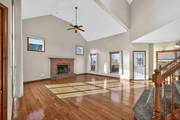 a view of an empty room with wooden floor fireplace and a window