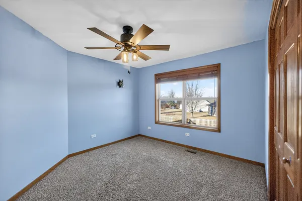an empty room with windows and fan