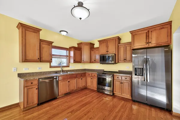 a kitchen with stainless steel appliances granite countertop a sink and wooden floors