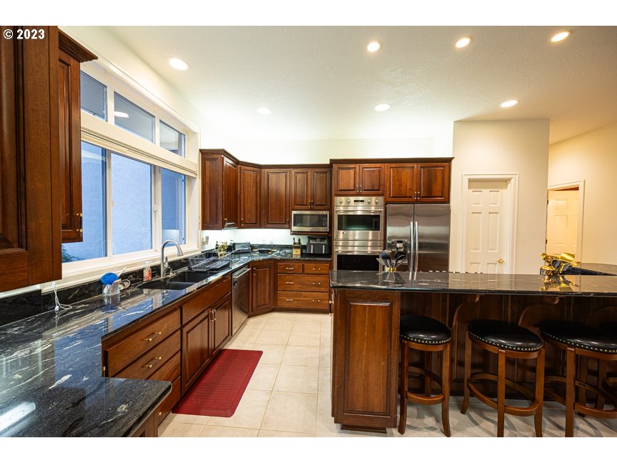3338 Lakeside Drive Eugene, OR 97401 - Photo 16 of 45 a kitchen with stainless steel appliances kitchen island granite countertop a sink and cabinets
