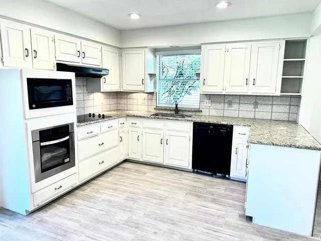 a kitchen with stainless steel appliances granite countertop a stove sink and cabinets